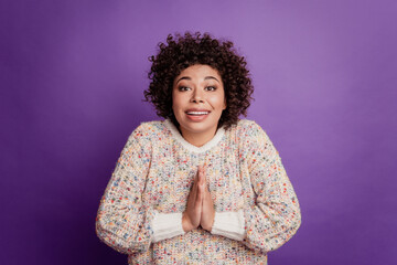 Portrait of pleading young woman hold palms together isolated on purple background