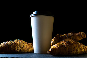 Croissant texture. French breakfast croissants, fresh pastry bread with paper coffee cup in bakery on dark stone background. Bread bakery products cafe concept.