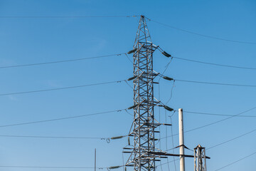 High voltage tower against a blue sky and city background