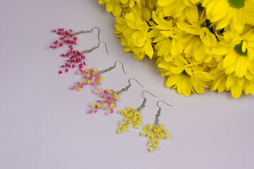 Colorful earrings and yellow flowers on violet background 