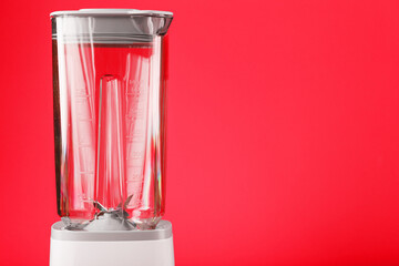 Electric blender with an empty cup on a red background.