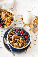 Homemade granola for to persons with nuts, berries and milk in blue plate on table for healthy breakfast, top view