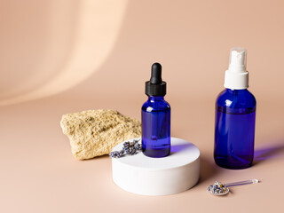 cosmetic products in blue glass bottles with dried lavender on beige background. Cosmetics branding mock-up. Clean organic beauty concept. copy space
