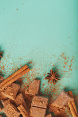 Milk chocolate with spices and cocoa on a green background.