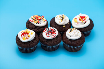 Homemade cupcakes with white icing and colorful sugar sprinkles on a blue background. Sweets for birthday, Valentine's day, children's holiday, Easter