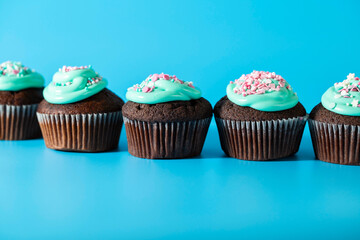 Cupcakes with turquoise icing and sugar sprinkles in the form of pink hearts and stars. Sweets for birthday, Valentine's day, children's holiday, Easter. Side view