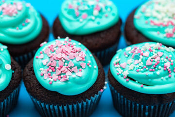 Chocolate muffins with turquoise glaze and sugar shaped sprinkles. Sweet holiday food close-up