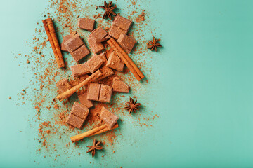 Milk chocolate with spices and cocoa on a green background.