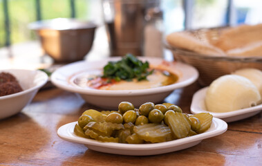 Arabic traditional cuisine.  Hummus on plate with parsley decorate in table pita, olives with pickle, falafel, stuffed dolma. Mediterranean appetizer party idea. on wooden background. Side view