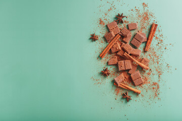 Milk chocolate with spices and cocoa on a green background.