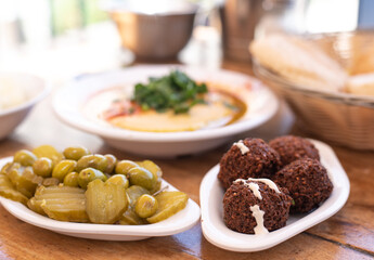 Arabic traditional cuisine. Hummus on plate with parsley decorate in table pita, olives with pickle, falafel, stuffed dolma. Mediterranean appetizer party idea. on wooden background. Side view