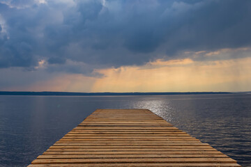 wooden pier on sea coast under dramatic cloudy sky