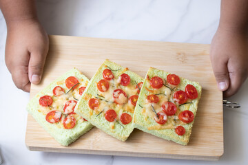Pandan flavor bread topped with baked tomatoes, cheese sprinkled with rosemary