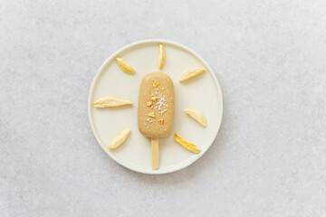 Popsicle with cashews chocolate, mango pieces and coconut on a plate. Sugar, gluten and lactose free. Horizontal orientation, top view.