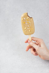 Vegan popsicle with chocolate cashews, mango pieces and coconut in hand. Sugar, gluten and lactose free.