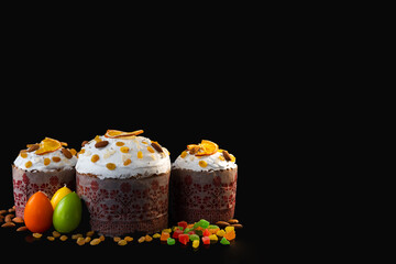Traditional Easter cakes on black background. Space for text. Migdal, candied fruits, colorful eggs and raisins, decor. Orthodox treat.