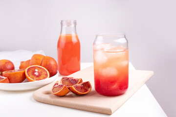 Fruit water in a glass with ice cubes, blood orange lemonade, summer refreshing drink on a white background.