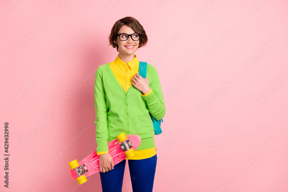 Sticker Photo of curious happy young brown bob haired student girl look empty space hold longboard rucksack isolated on pink color background