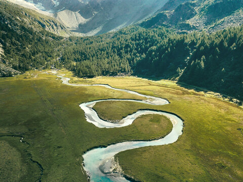 Aerial view of a winding river carrying sediments from the glacier in the Preda Rossa Valley, Val Masino, Lombardy, Italy.