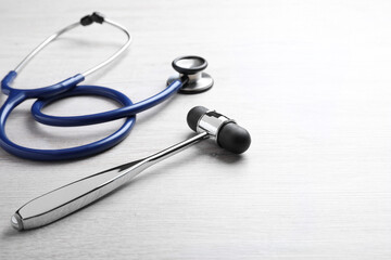Reflex hammer with stethoscope on light wooden background, closeup. Nervous system diagnostic