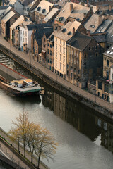 A barge crosses the Sambre next to houses at sunset.