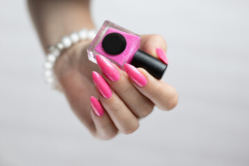 Woman's hands with long nails and neon pink fuchsia bottle manicure with nail polish