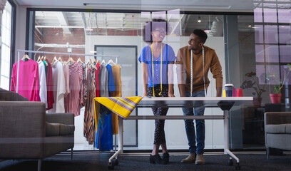 Diverse male and female fashion designers at work discussing and looking at sketches