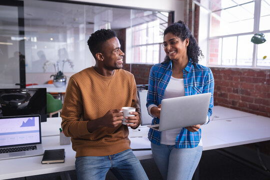 Happy Diverse Male And Female Colleagues At Work Standing Discussing In Front Of Laptop