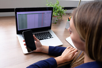 Caucasian businesswoman sitting at desk having video call conversation using smartphone