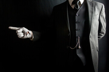 Portrait of Butler or Servant in Dark Suit and White Gloves Pointing the Way. Concept of Service...