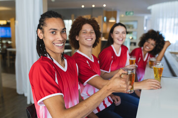 Diverse group of male and female sports fans having beer watching game at bar