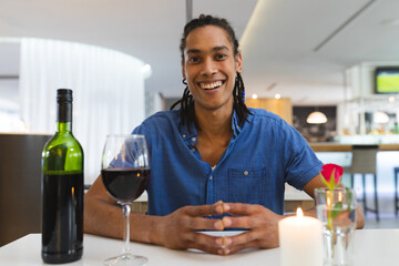 Mixed race man sitting at table in restaurant on dinner smiling