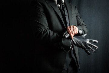 Portrait of Businessman in Dark Suit Pulling on Black Leather Gloves. Well Dressed Mafia Hit Man. Gentleman Assassin. - obrazy, fototapety, plakaty