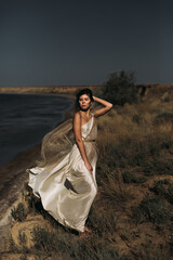 Close-up A beautiful girl in a stilted suit stands on a mountain above the sea, a lake on a sunny day.