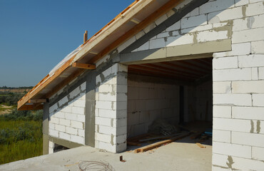 A close-up on the construction of a brick attic with a large window and roofing construction with wooden roof eaves.