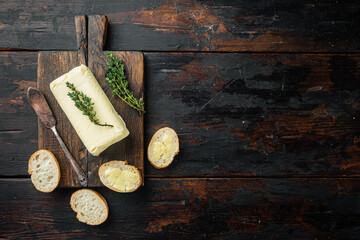 A piece of butter, on old dark  wooden table background, top view flat lay  with copy space for text