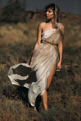 A beautiful girl in a stilted suit stands on a mountain above the sea, a lake on a sunny day.