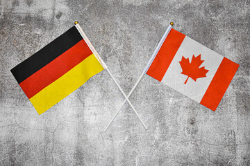 Hand flags of Germany and Canada on Abstract background