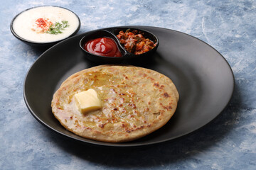 Traditional Indian food Aloo paratha or potato stuffed flat bread. served with pickle  tomato ketchup and curd, 