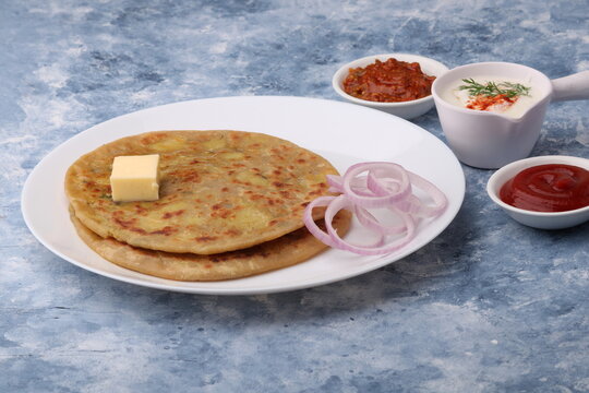 Traditional Indian food Aloo paratha or potato stuffed flat bread. served with pickle  tomato ketchup and curd, butter, onion.