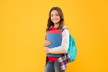 Happy school child hold study books on September 1 yellow background, back to school