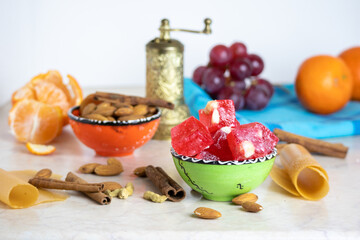 Turkish delight or lokum in a green bowl with grapes, mandarines, nuts, spices - a great arabic dessert.