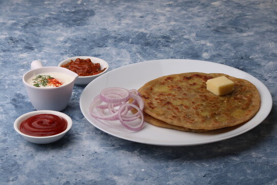Traditional Indian food Aloo paratha or potato stuffed flat bread. served with pickle  tomato ketchup and curd, butter, onion.