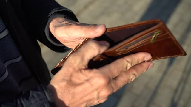 An elderly man holds an empty purse. The concept of poverty in retirement