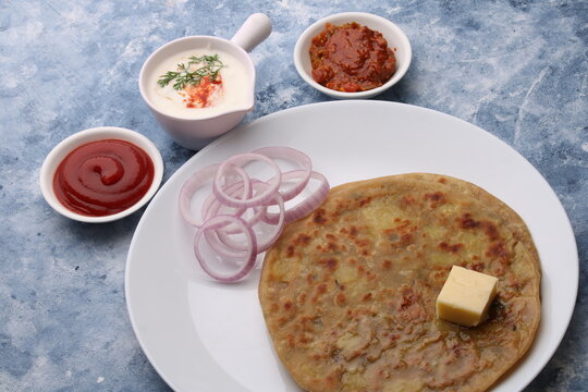 Traditional Indian food Aloo paratha or potato stuffed flat bread. served with pickle  tomato ketchup and curd, butter, onion.