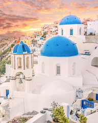 Sunset cityscape and orthodox church In blue and white In famous greek island Santorini In Cyclades region.