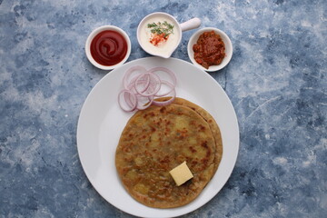 Traditional Indian food Aloo paratha or potato stuffed flat bread. served with pickle  tomato ketchup and curd, butter, onion.
