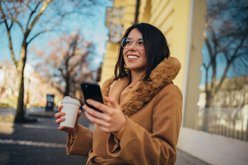 Hispanic woman using a smartphone and drinking coffee