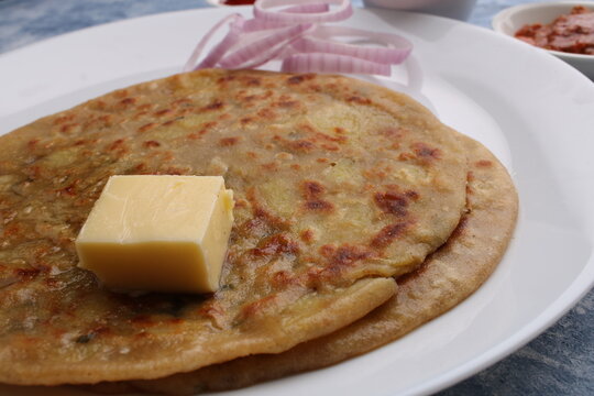 Traditional Indian food Aloo paratha or potato stuffed flat bread. served with pickle  tomato ketchup and curd, butter, onion.