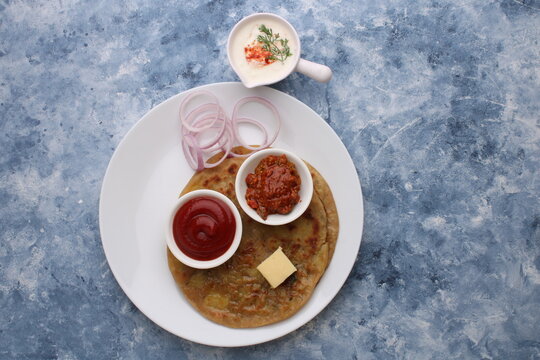 Traditional Indian food Aloo paratha or potato stuffed flat bread. served with pickle  tomato ketchup and curd, butter, onion.